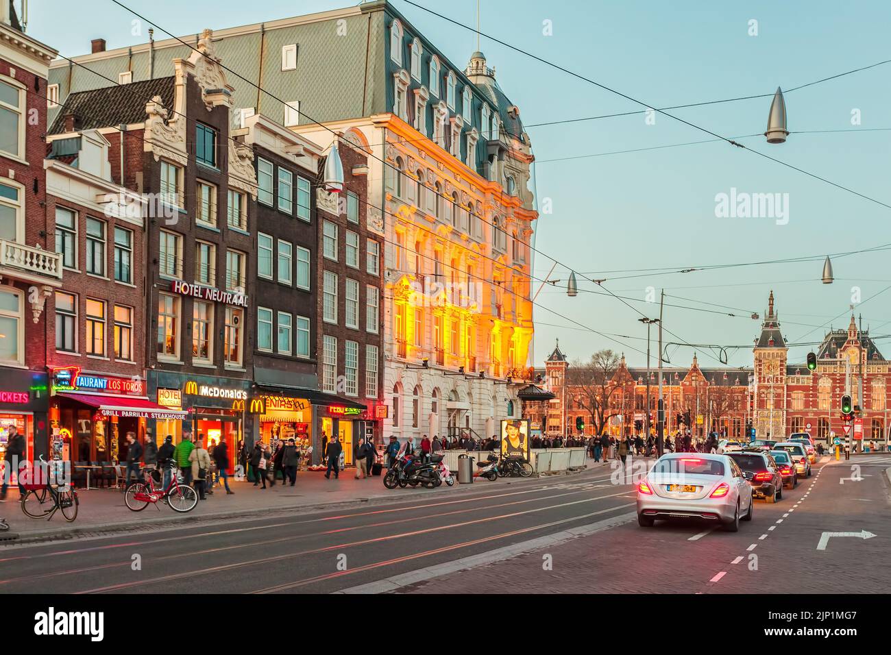 AMSTERDAM, PAESI BASSI - 12 MARZO 2015: Vista al tramonto del famoso Damrak con negozi, hotel e barche sui canali ad Amsterdam, Paesi Bassi Foto Stock