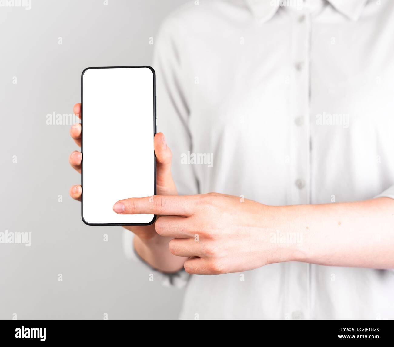 Indice premere il pulsante ok durante il mockup del telefono. Donna che tiene il modello Android con il display vuoto in posizione verticale. Tecnologie digitali nella vita moderna. Foto di alta qualità Foto Stock