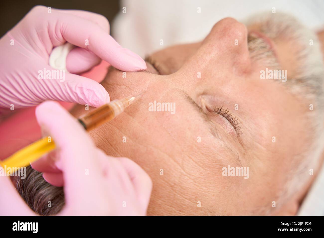 Il cosmetologo attraverso siringa inietta la bellezza nell'uomo nel salone di bellezza Foto Stock