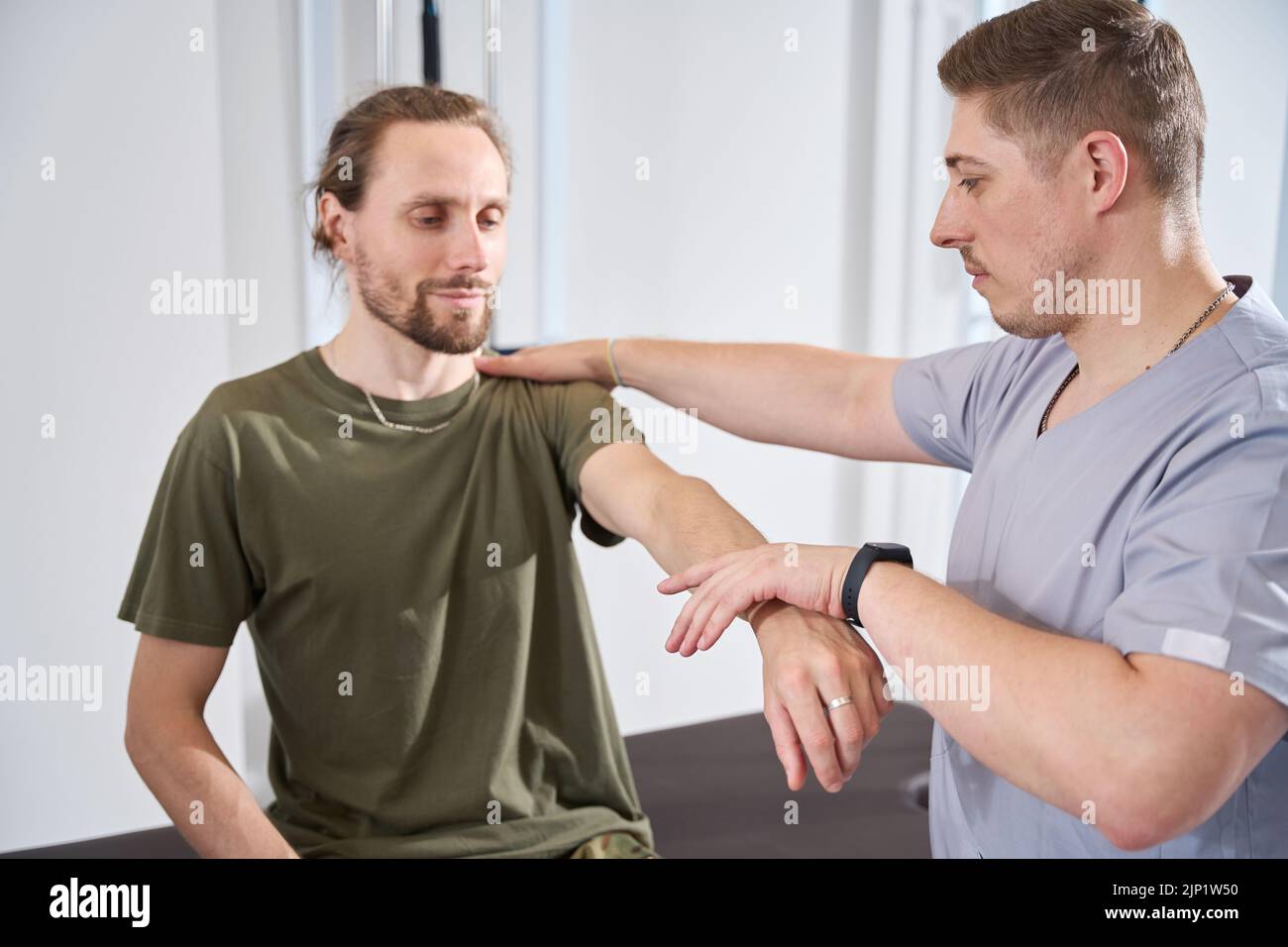 Un medico militare aiuta un soldato a sviluppare un braccio ferito Foto Stock