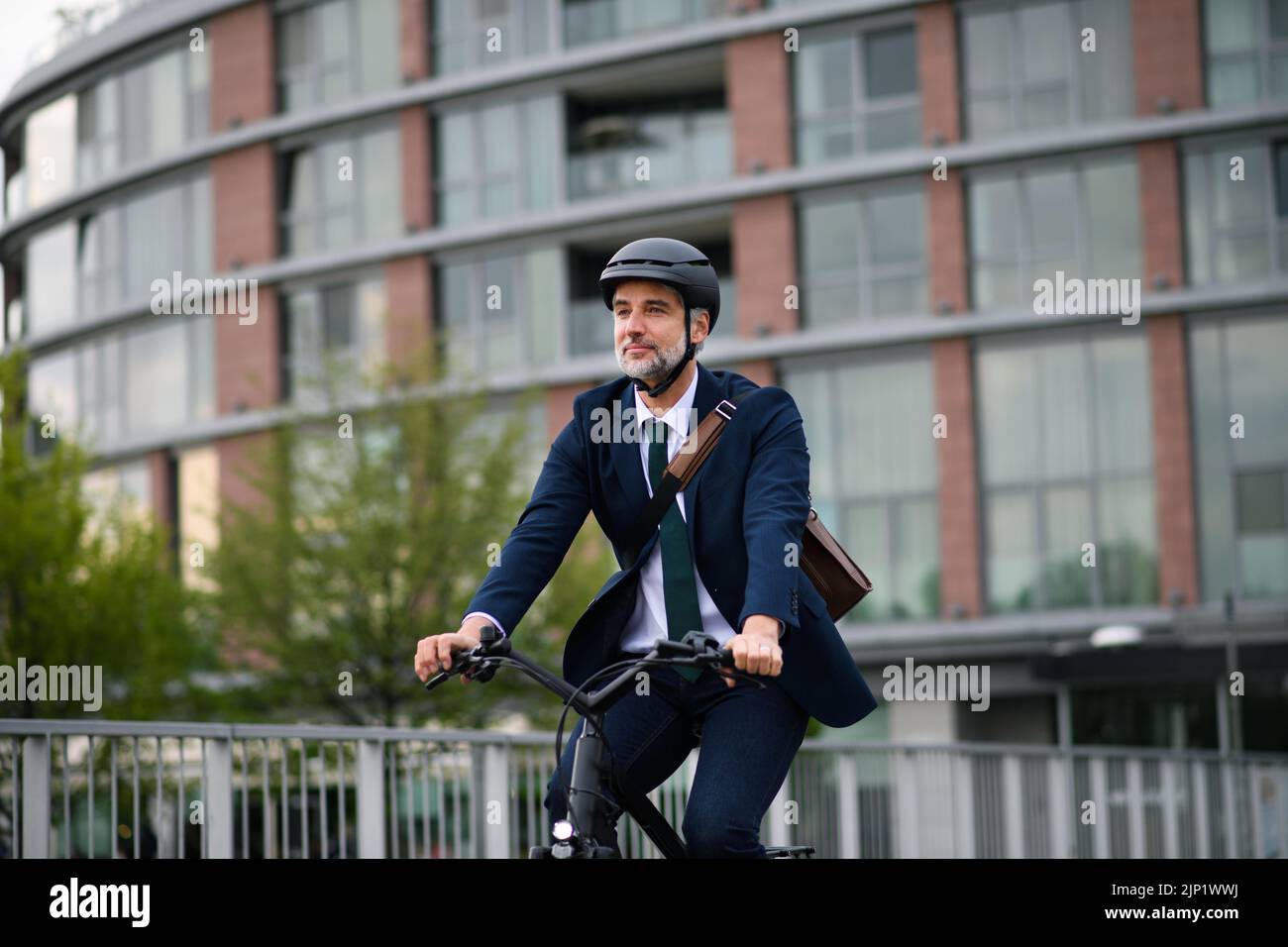 Uomo d'affari che viaggia per lavoro, in bicicletta in città, concetto di stile di vita sostenibile. Foto Stock