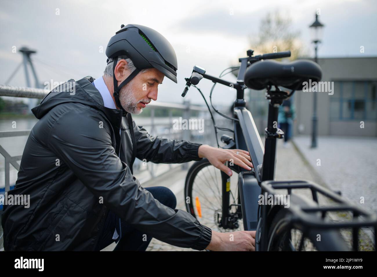 Ritratto di uomo d'affari in bicicletta casco che fissa la sua bicicletta, concetto di stile di vita sostenibile. Foto Stock