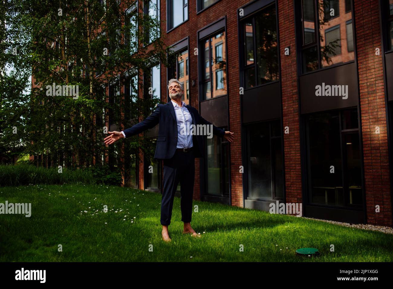 Uomo d'affari camminando a piedi nudi nel parco, sentendosi libero, concetto di equilibrio di vita di lavoro. Foto Stock