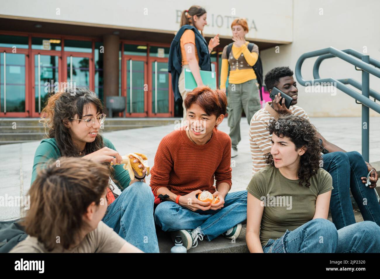 Studenti diversi che riposano su gradini per strada Foto Stock