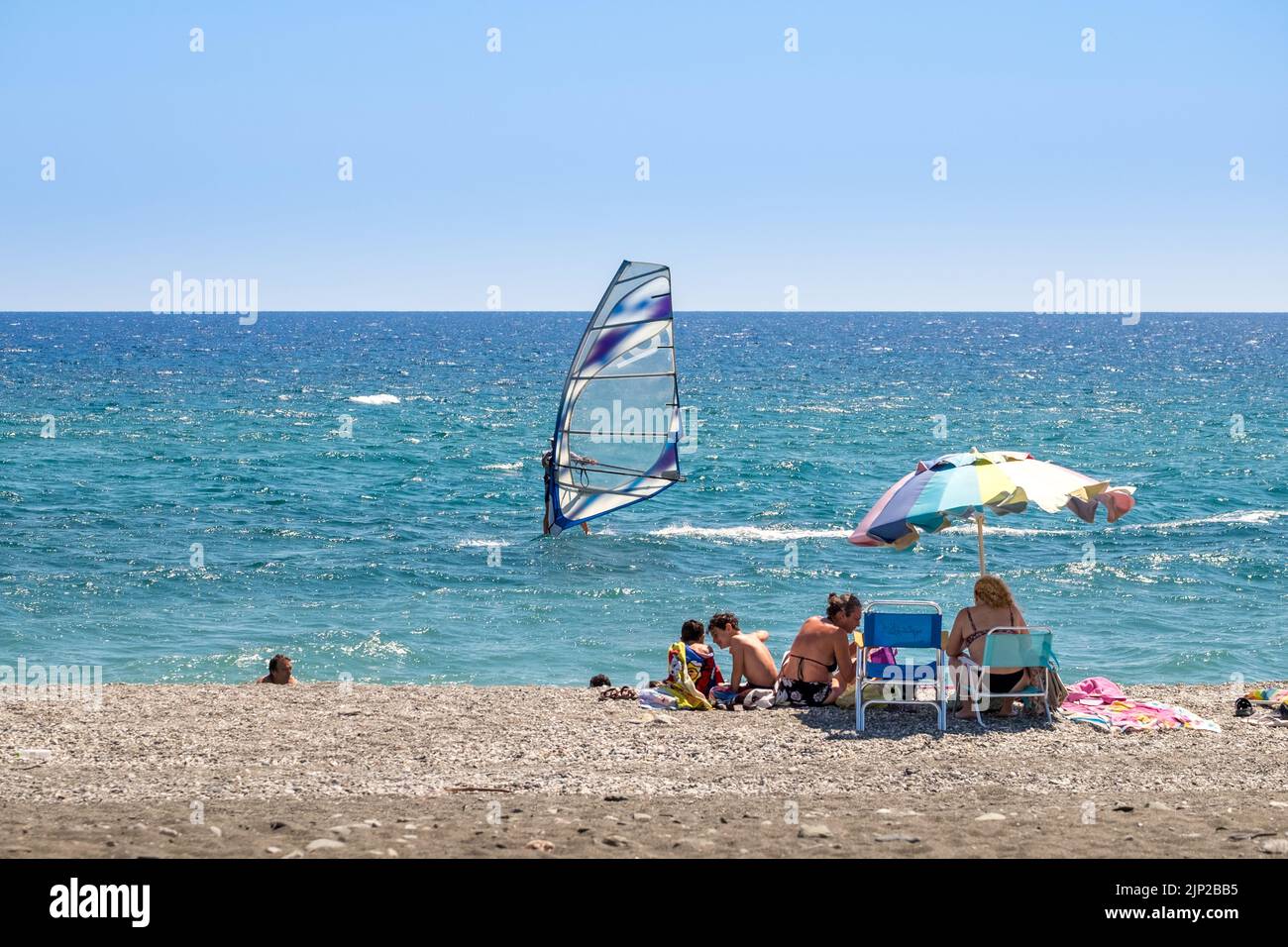 Famiglia in riva fissando un windsurf nel mare di Agiokampow spiaggia, Grecia Foto Stock