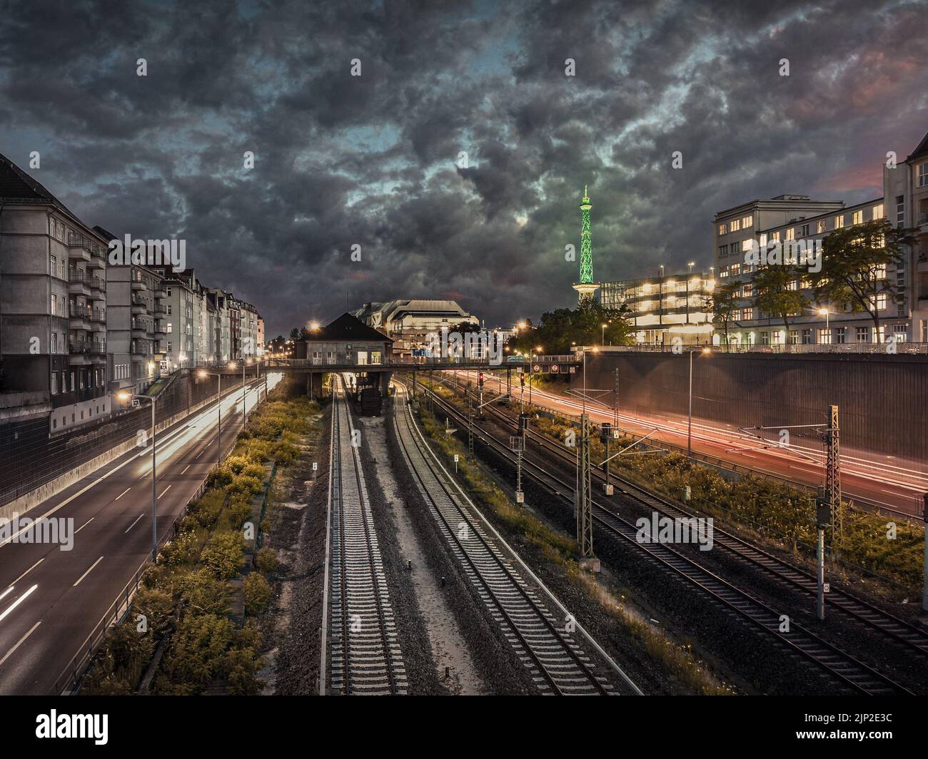 Una vista serale delle ferrovie, degli edifici di Berlino, della verde e luminosa torre della televisione da Berlino Ovest e delle strade con luci a lunga esposizione Foto Stock