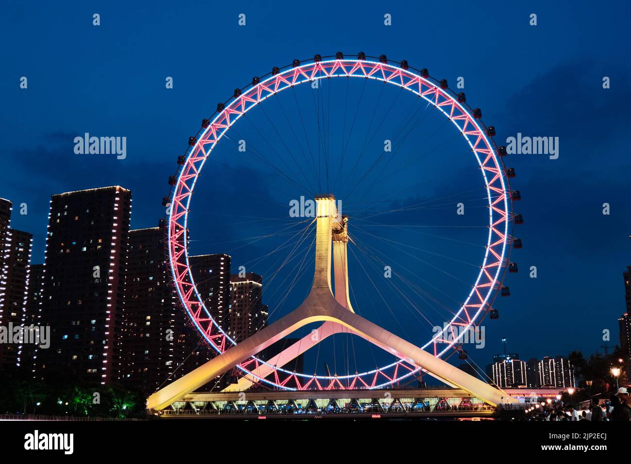 Una vista notturna del Tianjin Eye con luci scintillanti sullo sfondo di edifici moderni, Tianjin, Cina Foto Stock