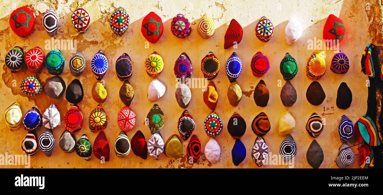 Tradizionale design marocchino lavorato a mano cappelli colorati appesi in file sul muro nel bazar medina della città - Essaouira, Marocco Foto Stock