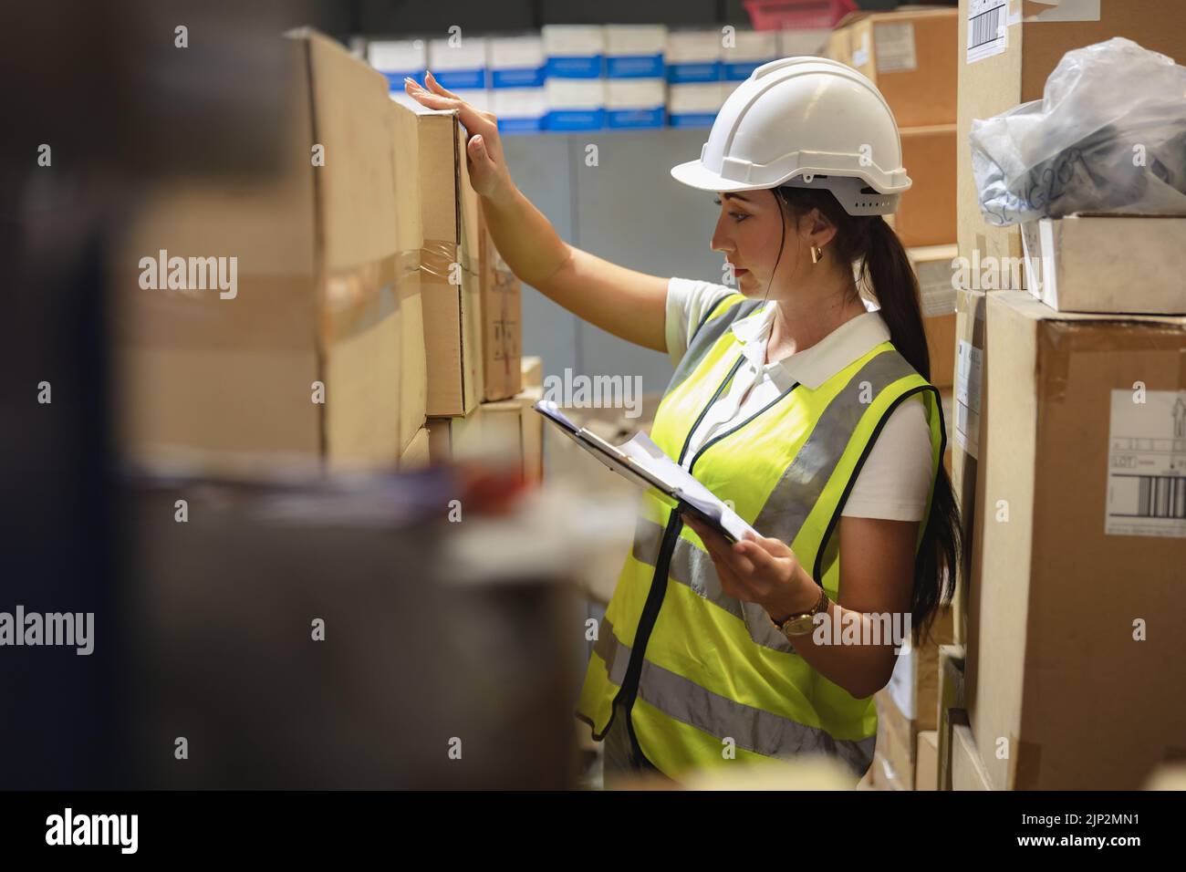 il personale di magazzino donna lavoro intende controllare attentamente le scorte di magazzino dei prodotti. Foto Stock