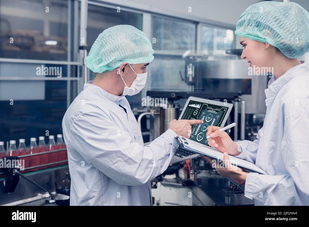 Lavoratore della fabbrica di alimenti e bevande che lavora insieme al monitor di igiene controllo miscela ingredienti macchina con computer portatile Foto Stock