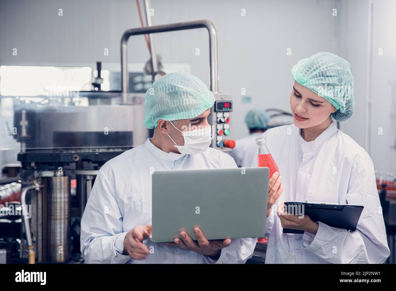 Lavoratore della fabbrica di alimenti e bevande che lavora insieme al monitor di igiene controllo miscela ingredienti macchina con computer portatile Foto Stock