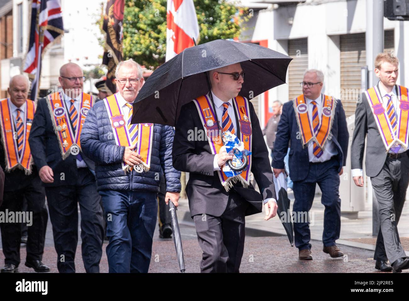 Ballymena, Regno Unito, 25th Giu 2022. Il Maestro adorabile di Ballygarvey Lodge si rifugia sotto l'ombrello durante una breve doccia a pioggia all'annuale mini-Twelfth. Foto Stock