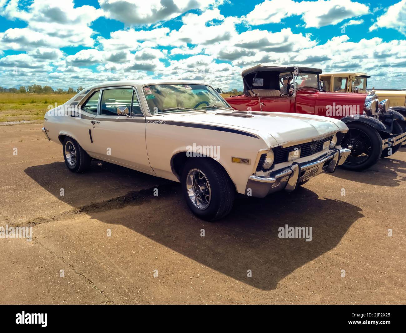 Old bianco sportivo Chevrolet Chevy 250 SS Super Serie 2 coupé 1970s costruito da GM parcheggiato in una pista di volo. Il bombardiere della seconda guerra mondiale sullo sfondo. CADEAA MNA 2022 Foto Stock