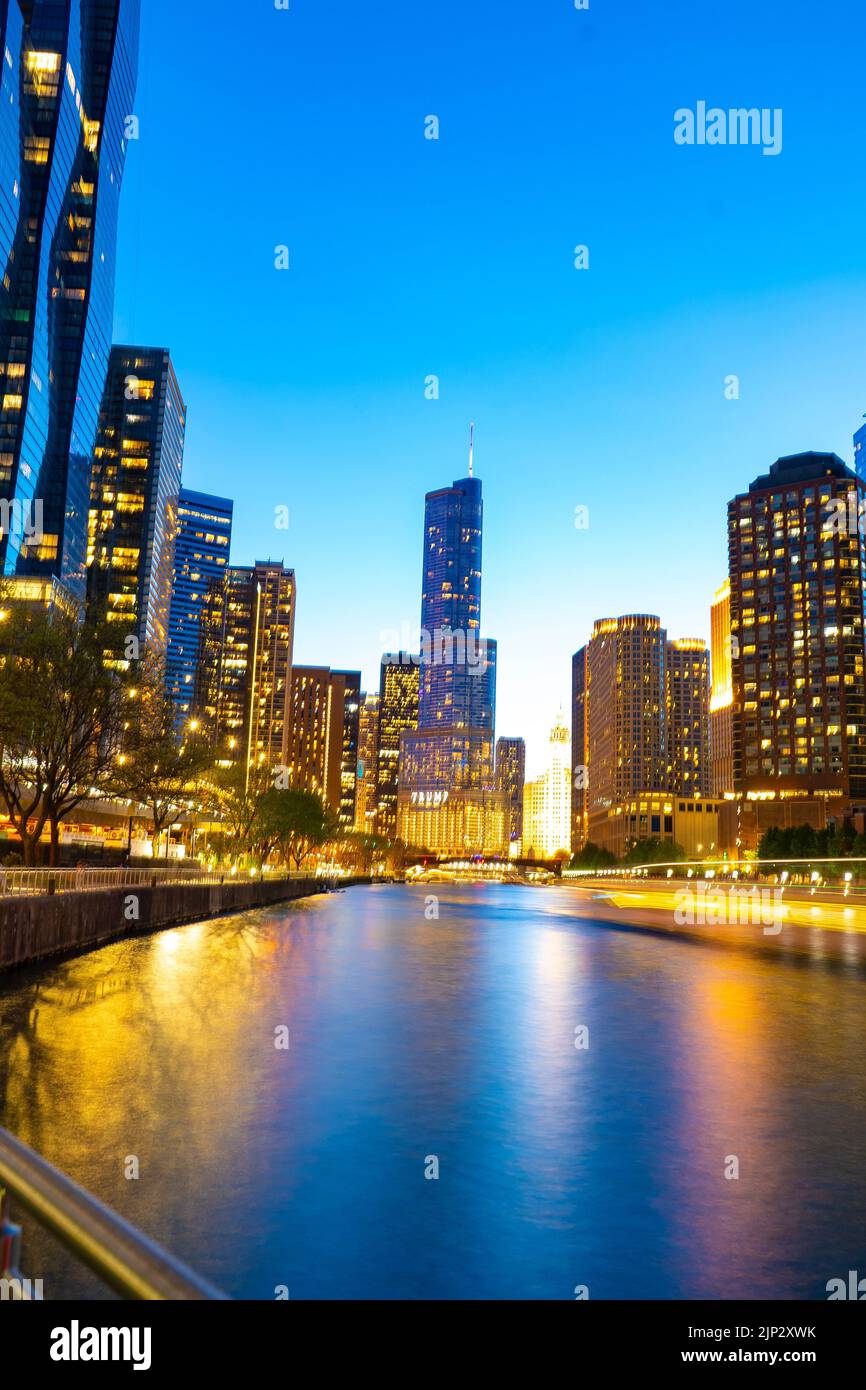 Una foto verticale di edifici illuminati sulla riva del fiume in serata. Chicago, Stati Uniti. Foto Stock