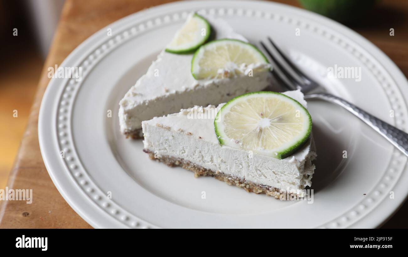 Un delizioso piatto di cremose crostate di lime ricoperte di fettine di lime Foto Stock