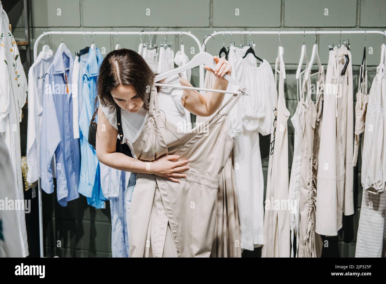 Moda sostenibile, moda lenta, shopping consapevole. Giovane donna Latina che acquista in un moderno negozio di abbigliamento. Foto Stock