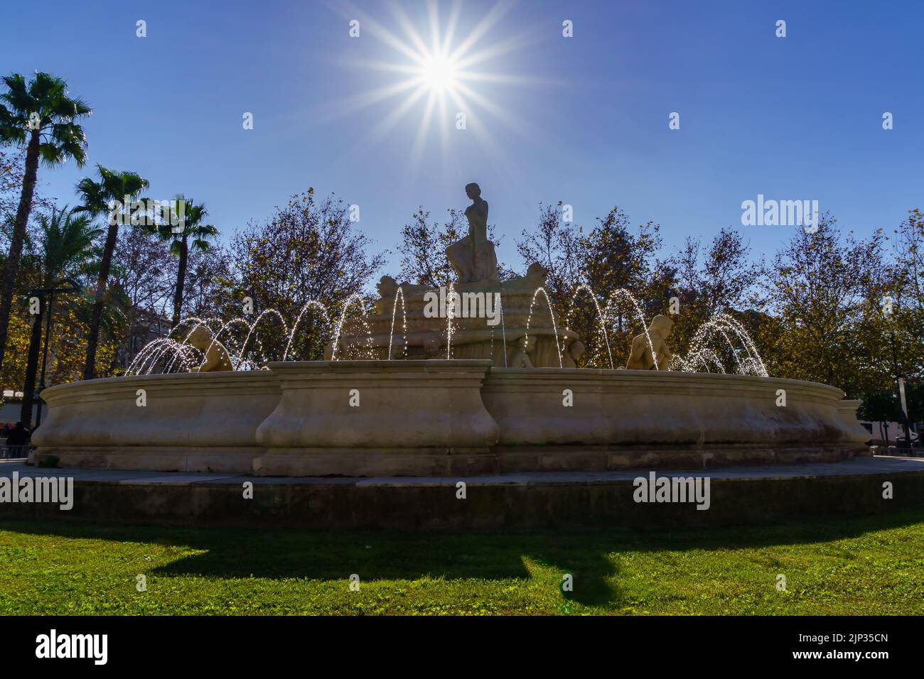 fontana con getti d'acqua in un parco della città di Siviglia, raggi di sole nel cielo blu senza nuvole. Spagna. Foto Stock