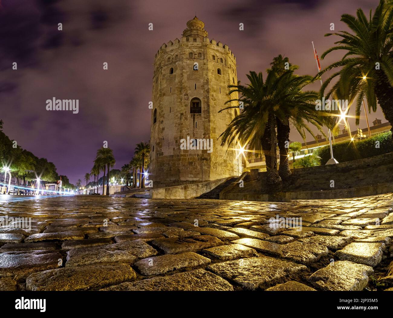 Torre del Oro a Siviglia, scena notturna con foto a lunga esposizione e basso punto di vista accanto al terreno acciottolato. Spagna. Foto Stock