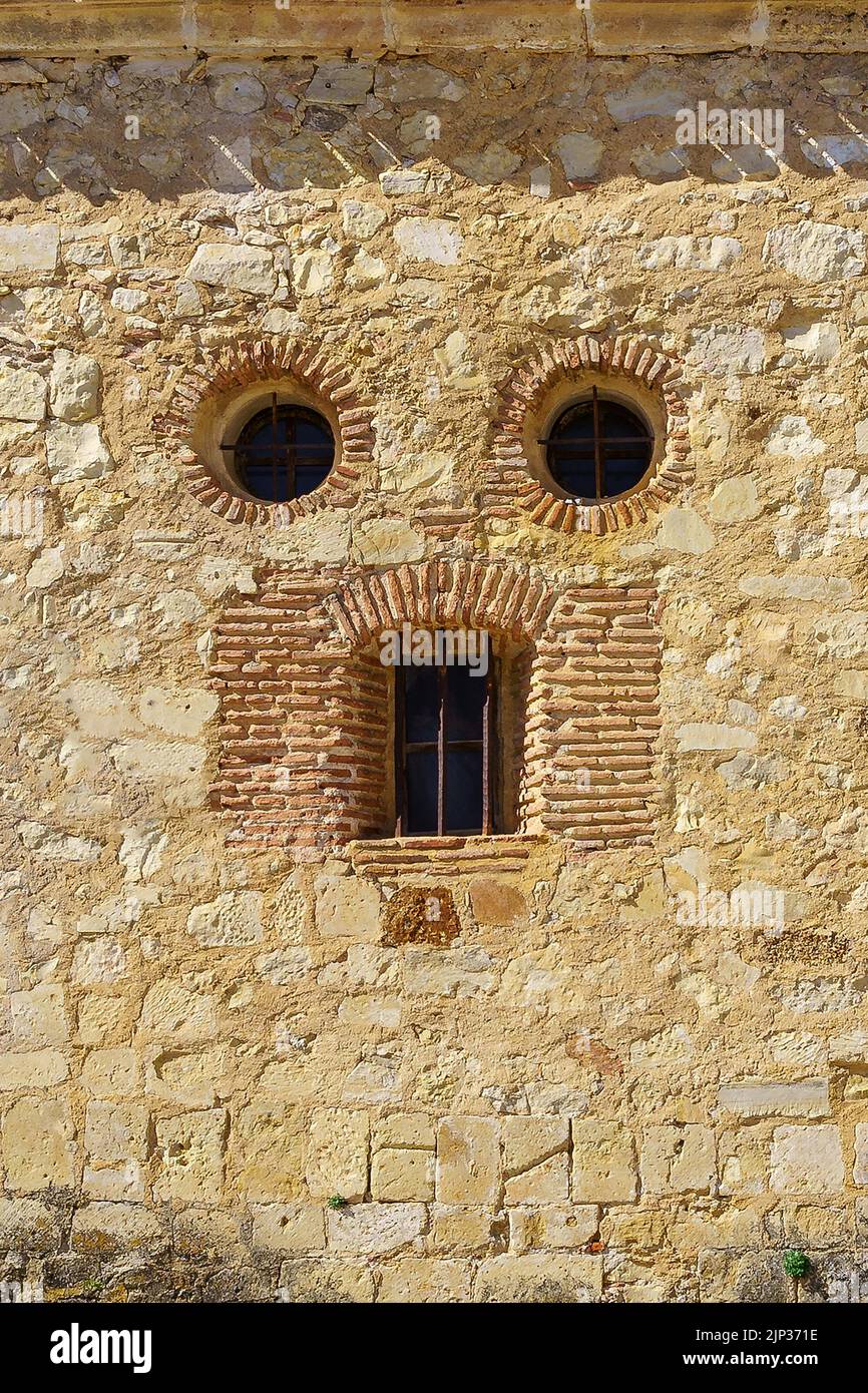 somiglianza di faccia in una vecchia facciata di casa di pietra, gli occhi e la bocca. Pedraza, Segovia. spagna. Foto Stock