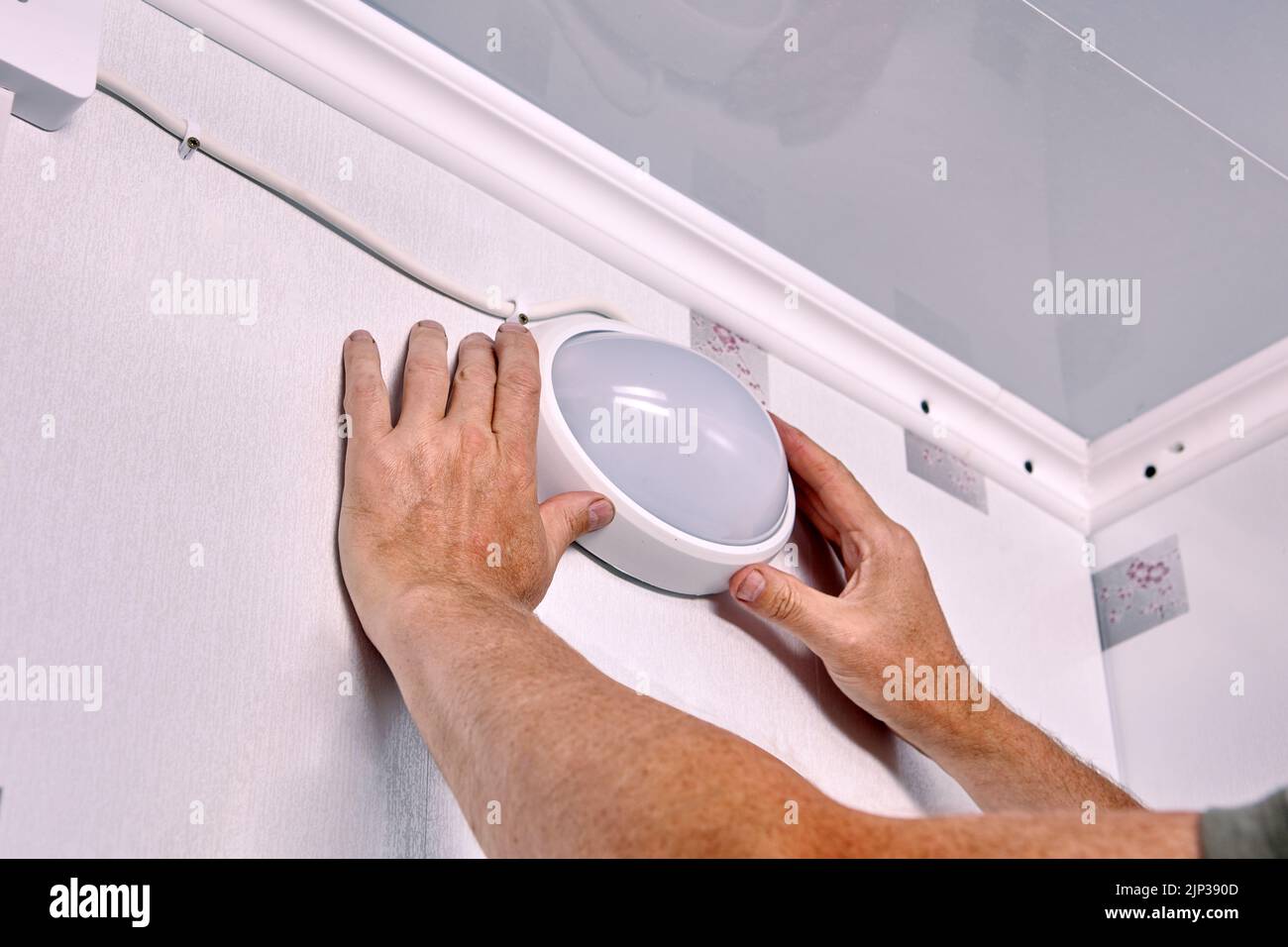 Montaggio del cappuccio dell'apparecchio di illuminazione, lampada collegata da elettricista in vetro smerigliato con attacco plafond sopra l'illuminatore. Foto Stock