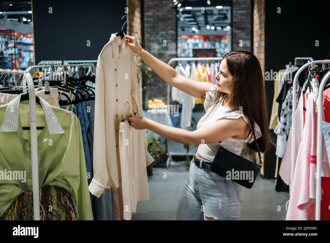 Moda sostenibile, moda lenta, shopping consapevole. Giovane donna Latina che acquista in un moderno negozio di abbigliamento. Foto Stock