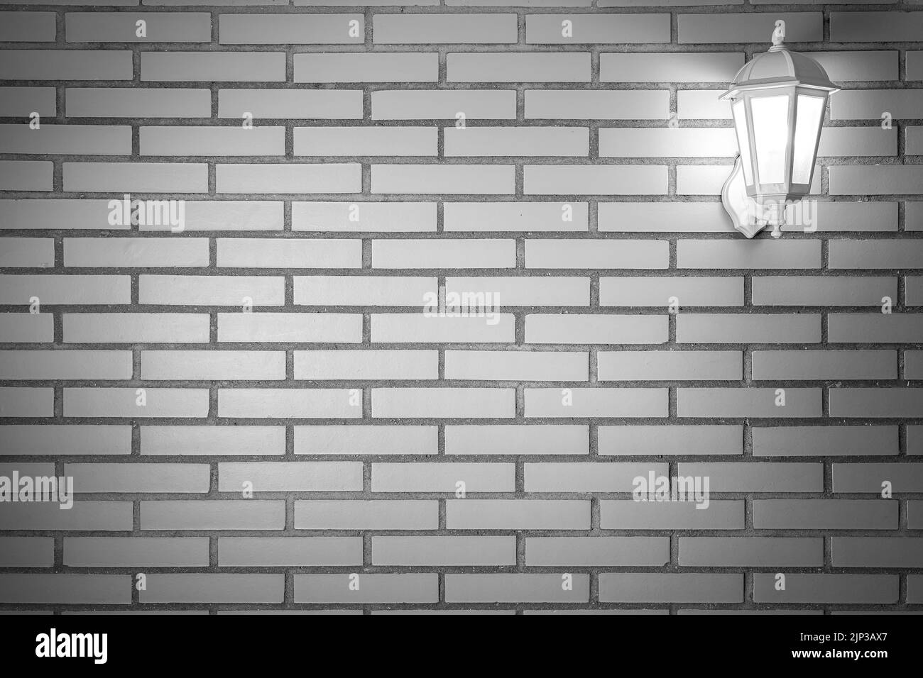 Sfondo a struttura in mattoni chiari con lanterna bianca con luce accesa. Copia spazio per il testo. Spagna. Foto Stock