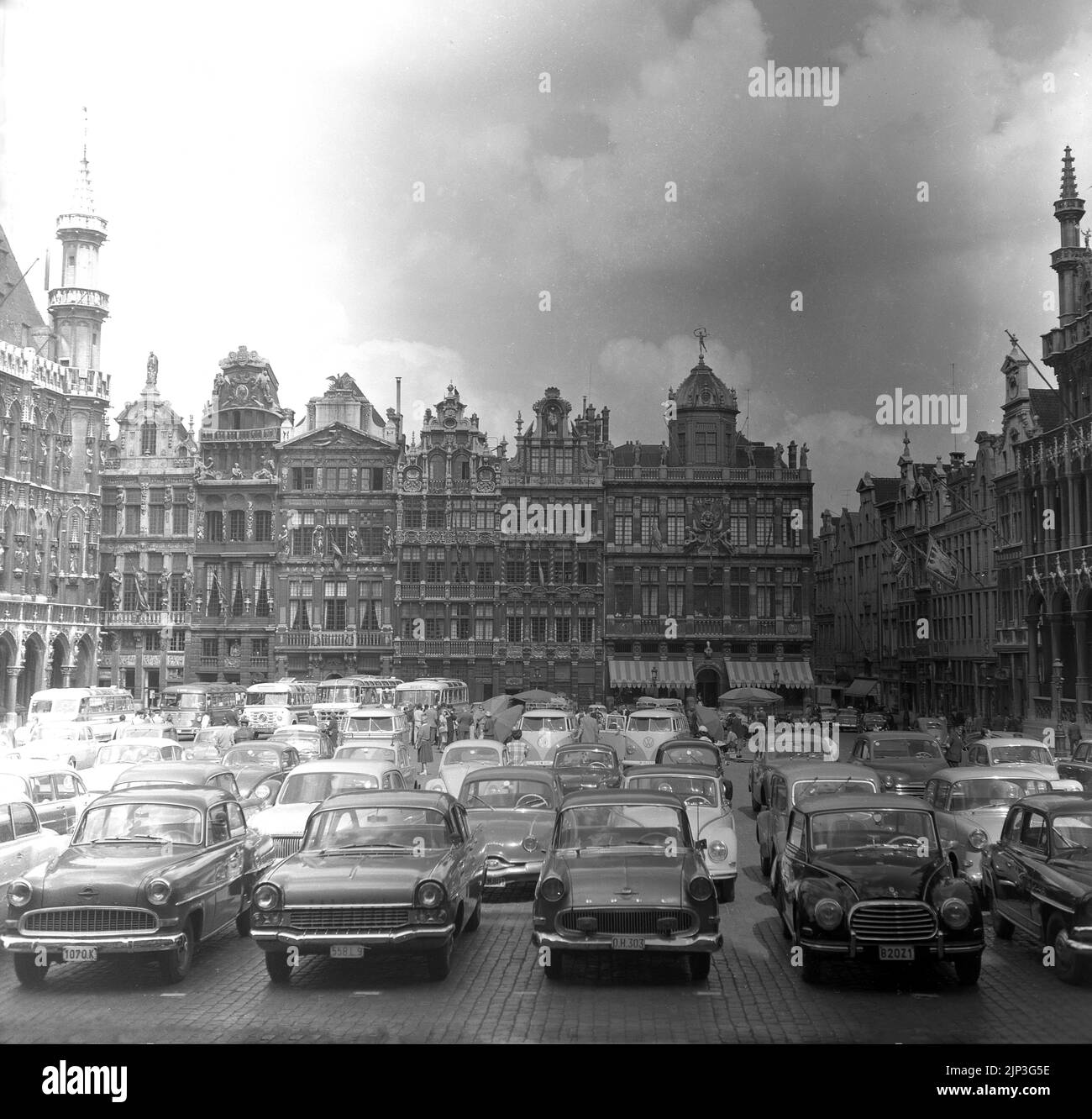 1960s, auto storiche dell'epoca parcheggiate presso la Grand-Place, la storica piazza centrale di Bruxelles, Belgio. In quest'epoca, si poteva parcheggiare un'auto di fronte agli edifici del 17th° secolo e così la piazza della città divenne un grande parcheggio. La macchina era moderna, la macchina era regale. All'inizio degli anni '1970s, un articolo del giornalista britannico John Lambert iniziò un movimento per cambiare questo e così nel marzo 1972, il parcheggio privato fu vietato da marzo a settembre, anche se le auto potevano ancora guidare attraverso la piazza. Fu solo nel 1990 che la piazza divenne completamente pedonale con tutto il traffico vietato. Foto Stock