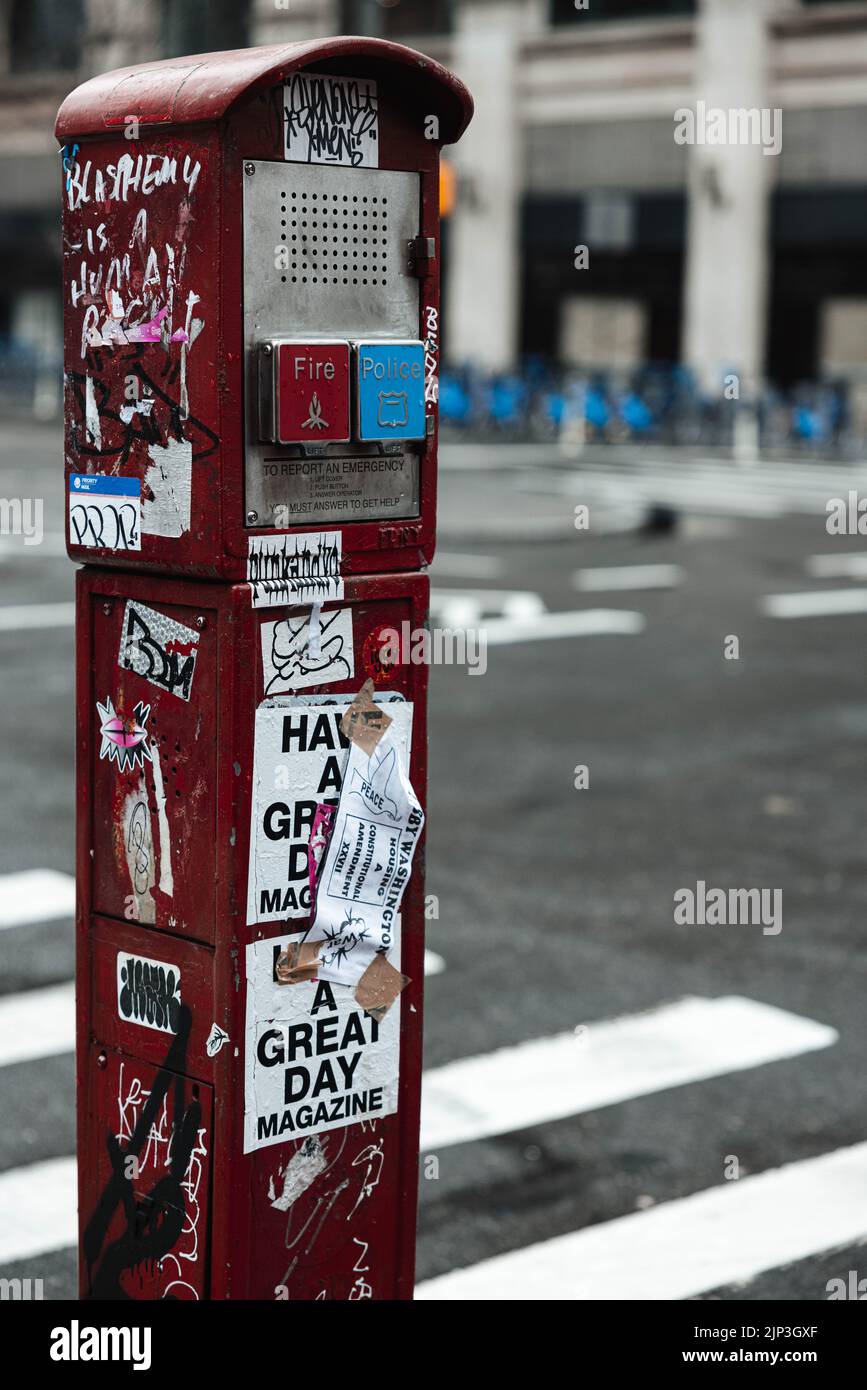 Uno scatto verticale di una scatola del sistema di segnalazione di emergenza coperta da adesivi a New York City Foto Stock