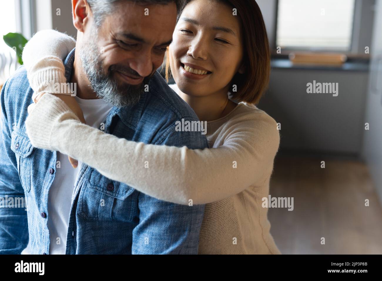 Felice coppia varia abbracciando e sorridendo con gli occhi chiusi in cucina Foto Stock