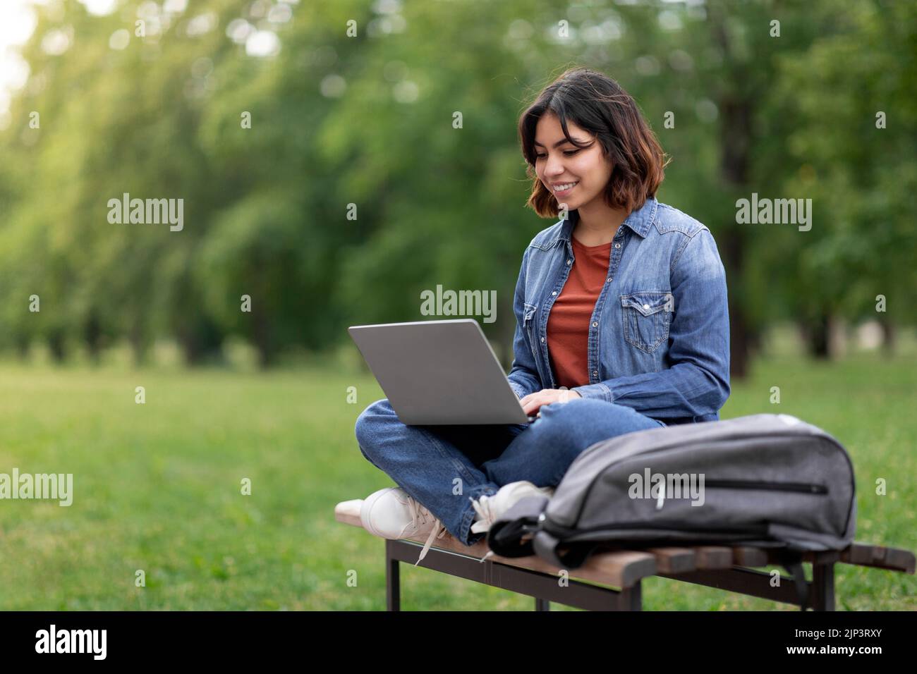 Apprendimento a distanza. Studentessa araba femmina che usa il notebook mentre si siede sul banco all'aperto Foto Stock