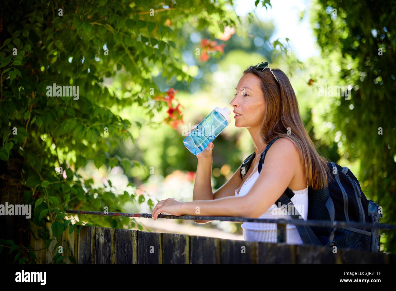 Donna che si rilassa all'aperto con una bottiglia d'acqua Foto Stock