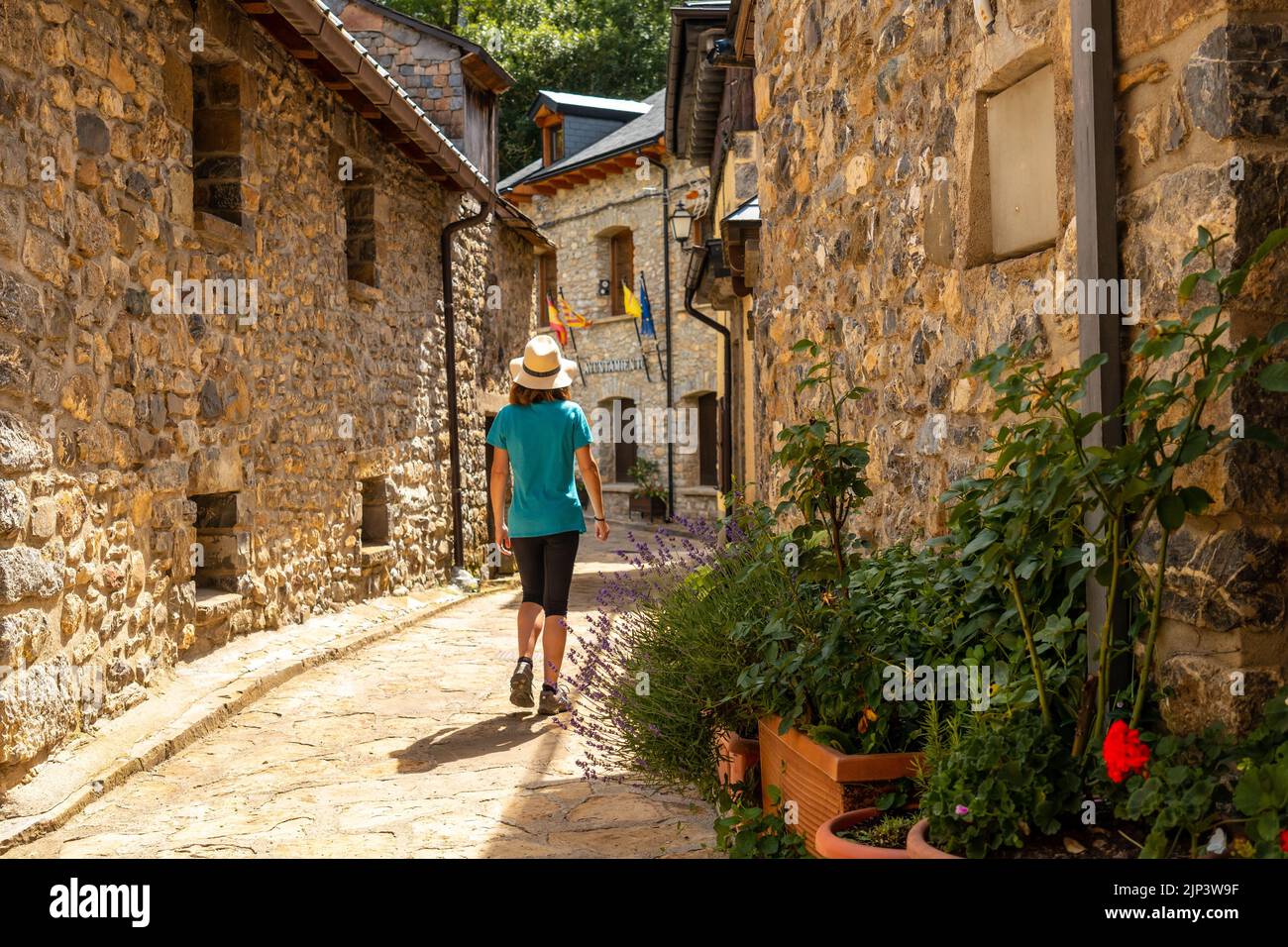 Una turista femminile in abiti casual a piedi in uno stretto vicolo tra vecchie case in Piedrafita de Jaca Foto Stock