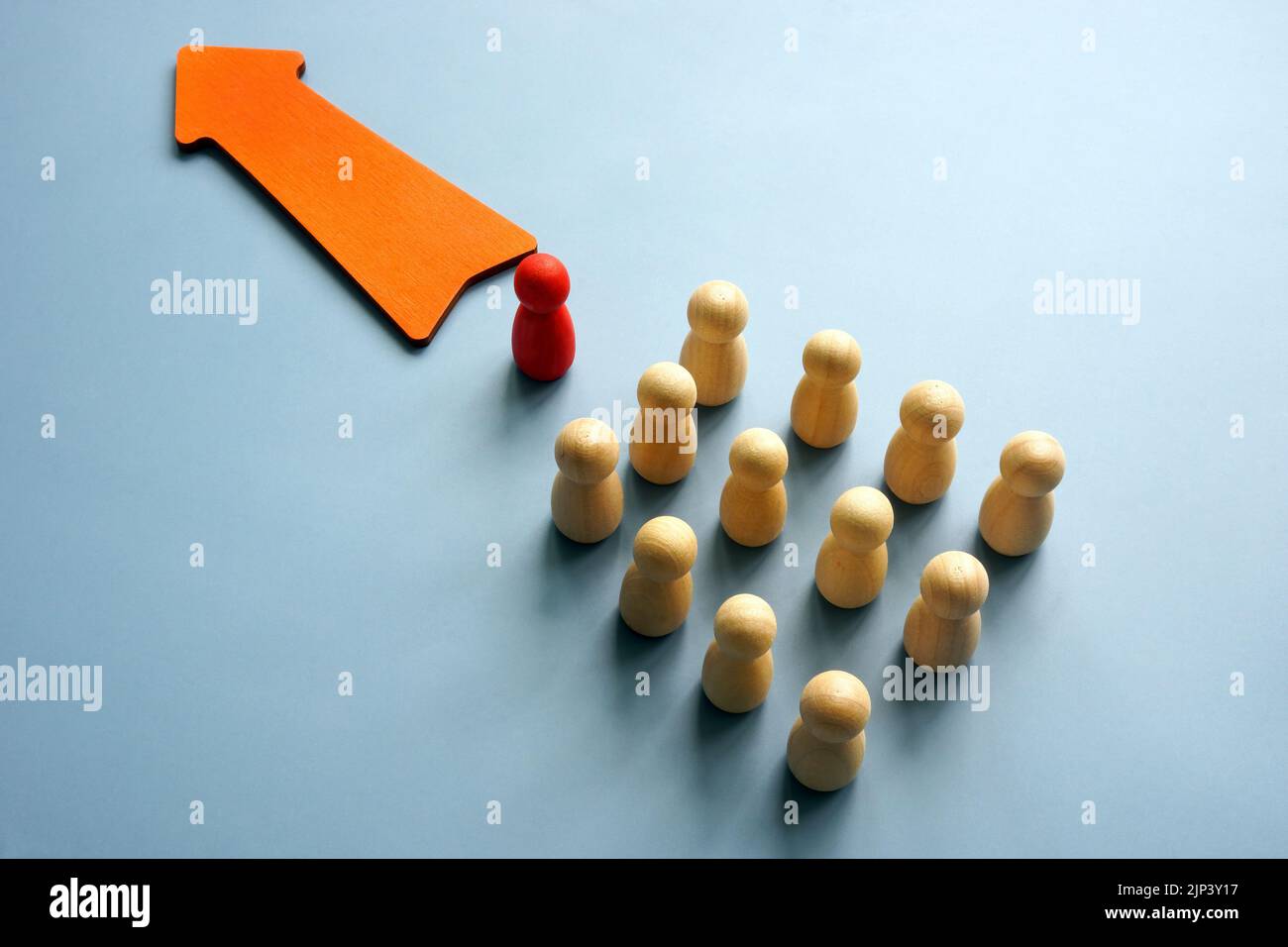 Concetto di leadership autocratica. Freccia e colonna di figurine con uno di fronte. Foto Stock