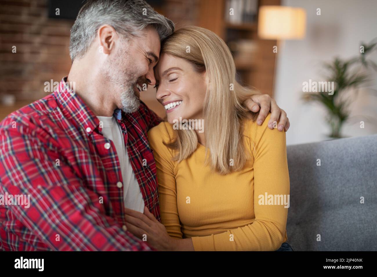 Allegro adulto europeo uomo e donna che abbracciano e godono di tenero momento e tempo libero, seduti insieme Foto Stock