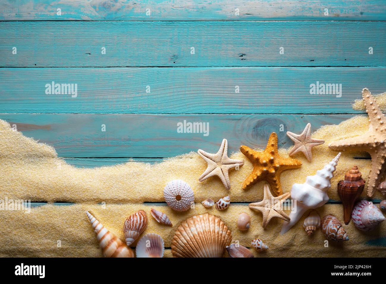 Vacanza e concetto estate con stelle marine e conchiglie su un tavolo in legno turchese con sabbia Foto Stock