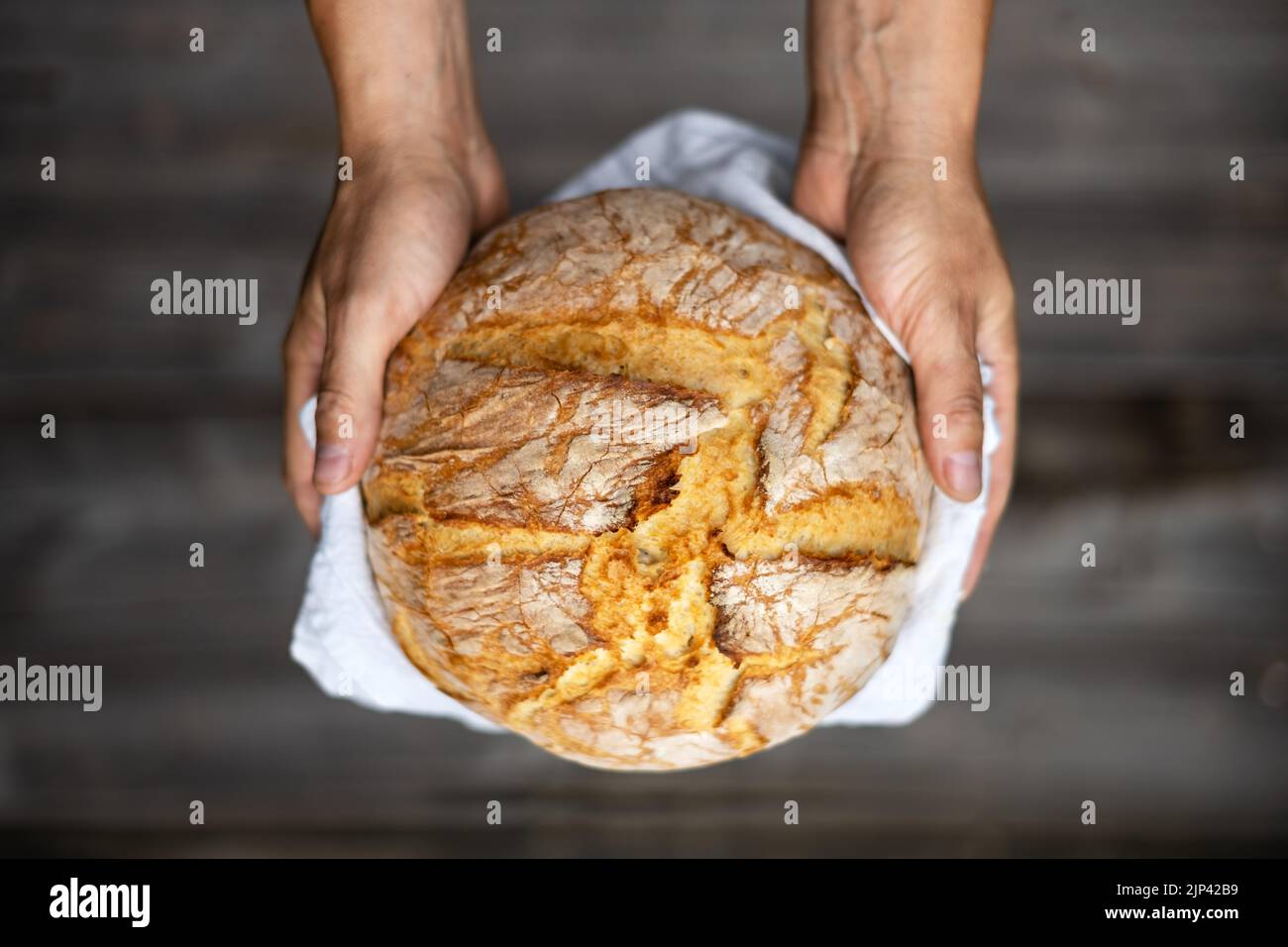 Pane tradizionale lievitato di pasta madre in panetteria mani su un rustico tavolo di legno. Fotografia alimentare sana Foto Stock