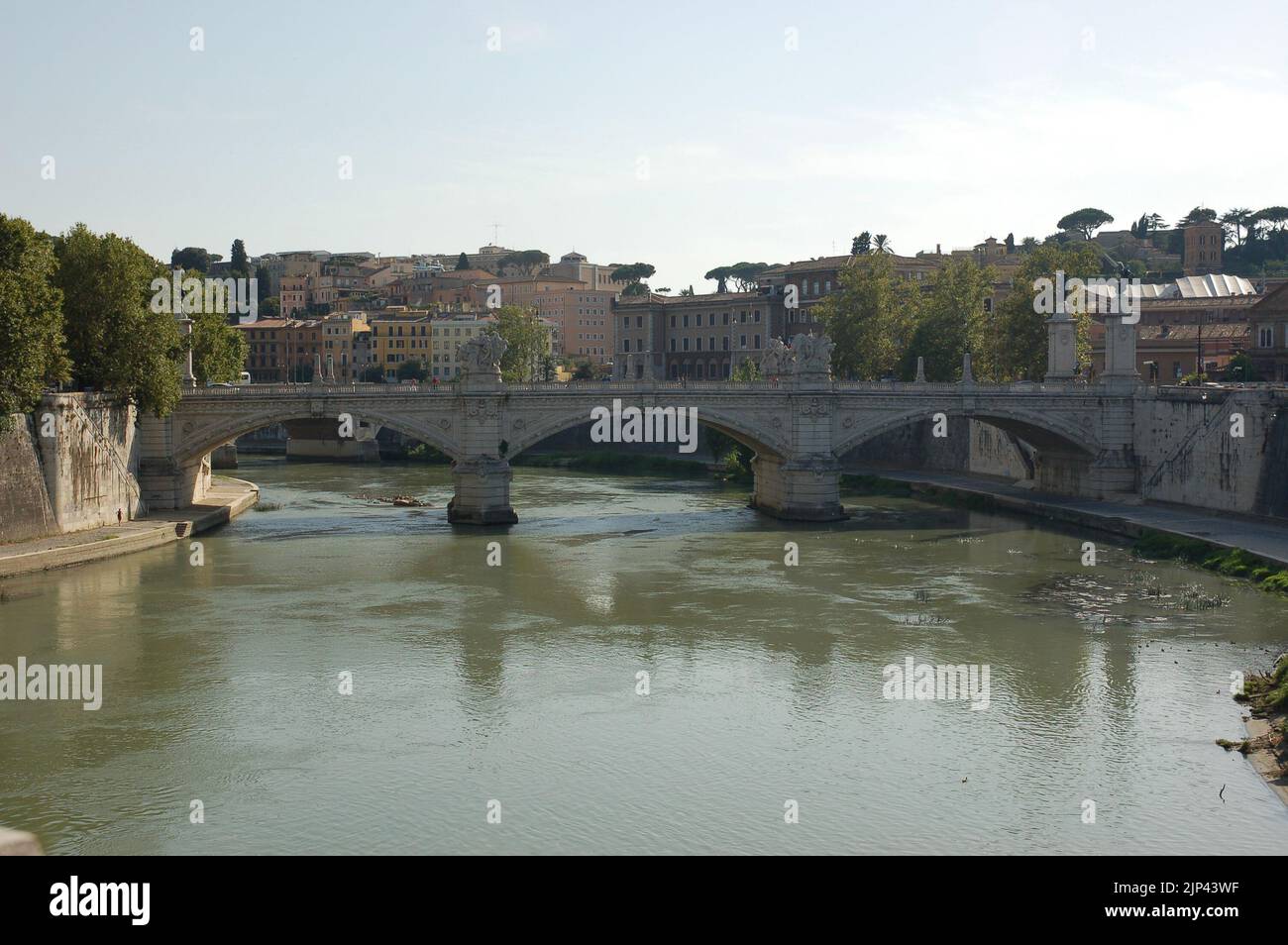 Il fiume Tevere a Roma con Ponte Vittorio Emanuele che collega le sponde e gli edifici residenziali sullo sfondo Foto Stock
