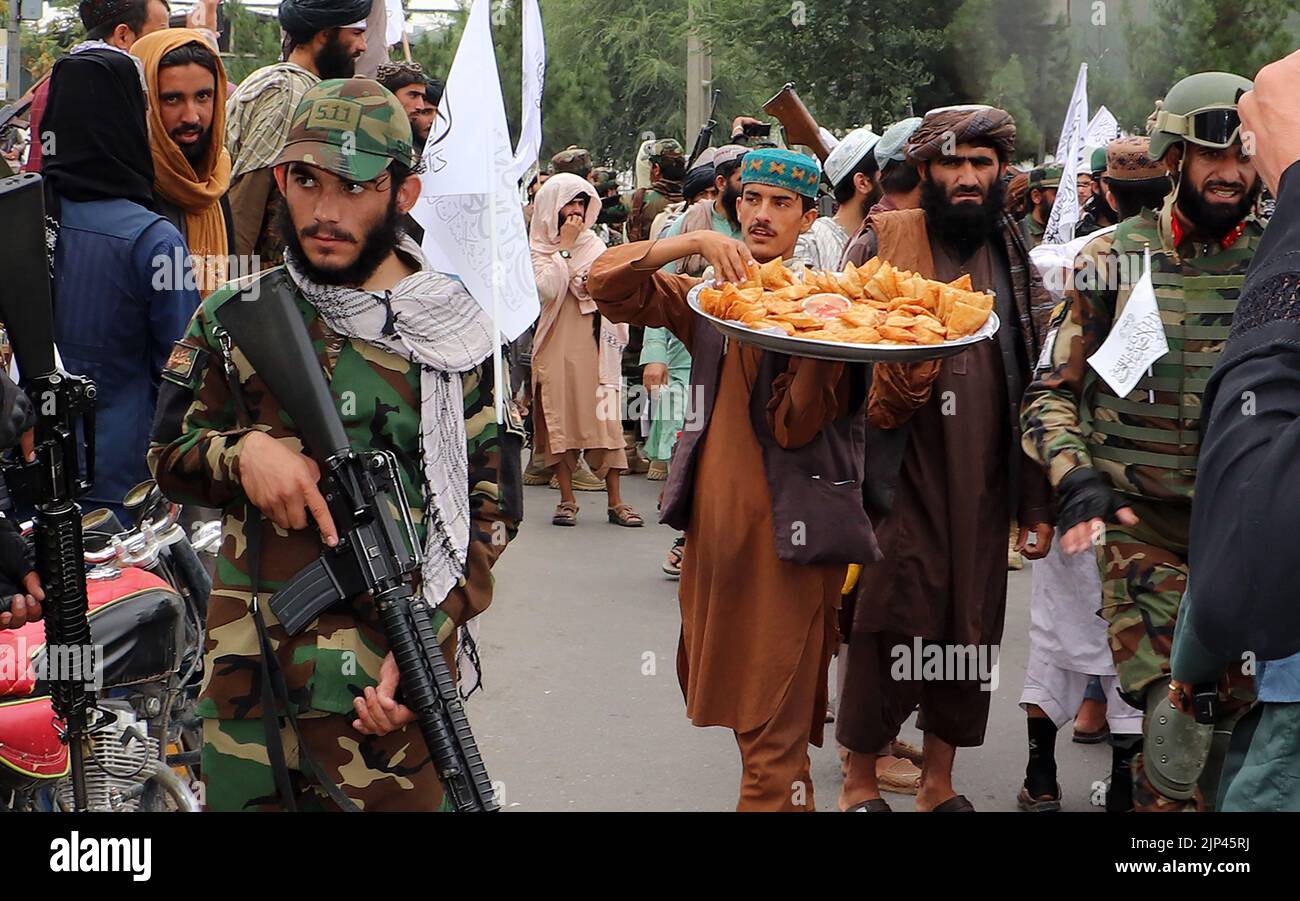 Kandahar, Afghanistan. 15th ago, 2022. I sostenitori talebani distribuiscono dolci durante una manifestazione a sostegno del primo anniversario della regola dei talebani a Kandahar, Afghanistan, lunedì 15 agosto 2022. Foto di Shekib Mohammadyl/UPI Credit: UPI/Alamy Live News Foto Stock