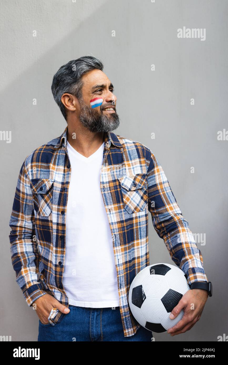 Felice uomo biraciale con il calcio e la bandiera dei paesi bassi sulla guancia Foto Stock