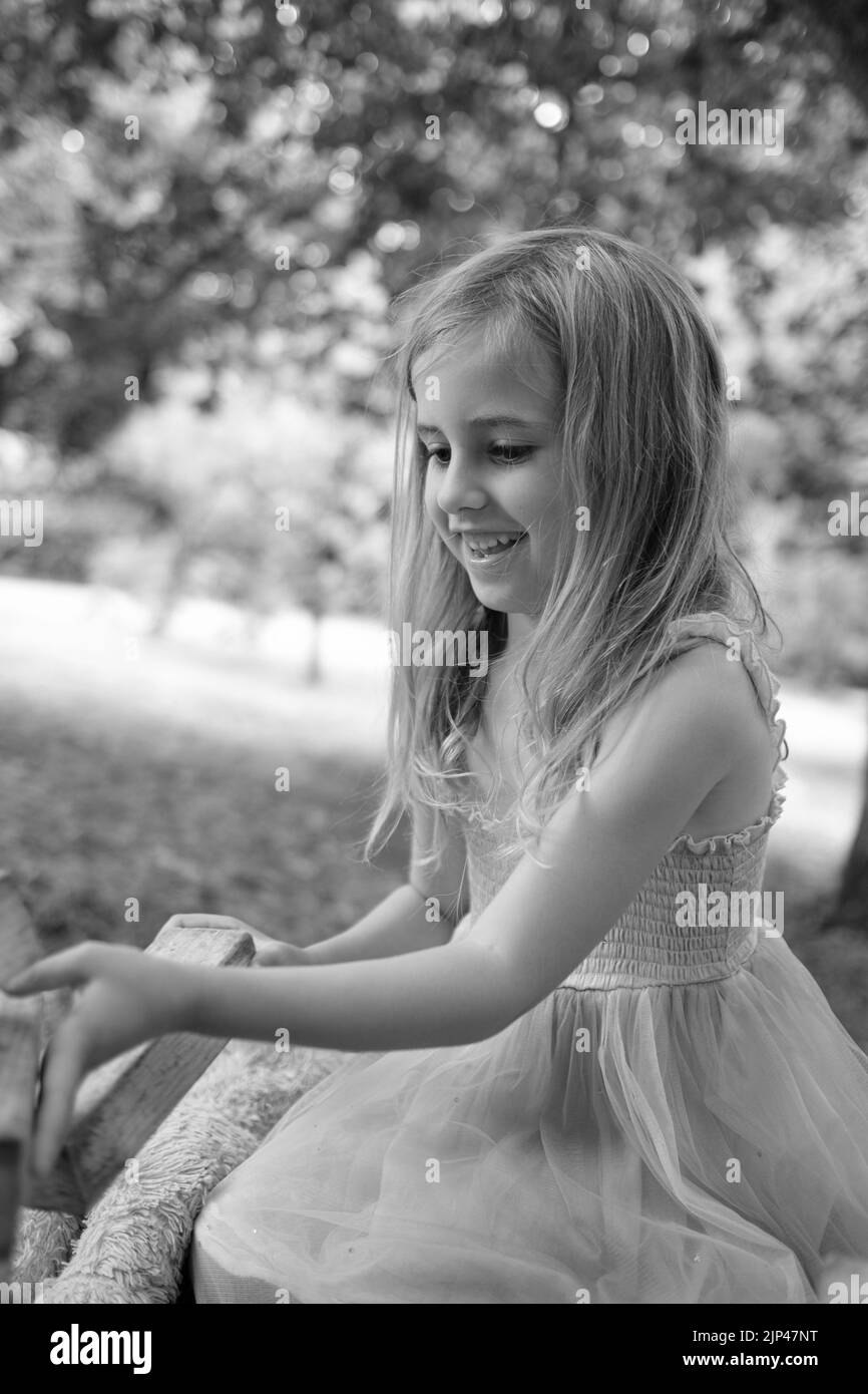 5yr bambina in rosa e blu vestito giocando con blocchi di legno in ambiente parco Foto Stock