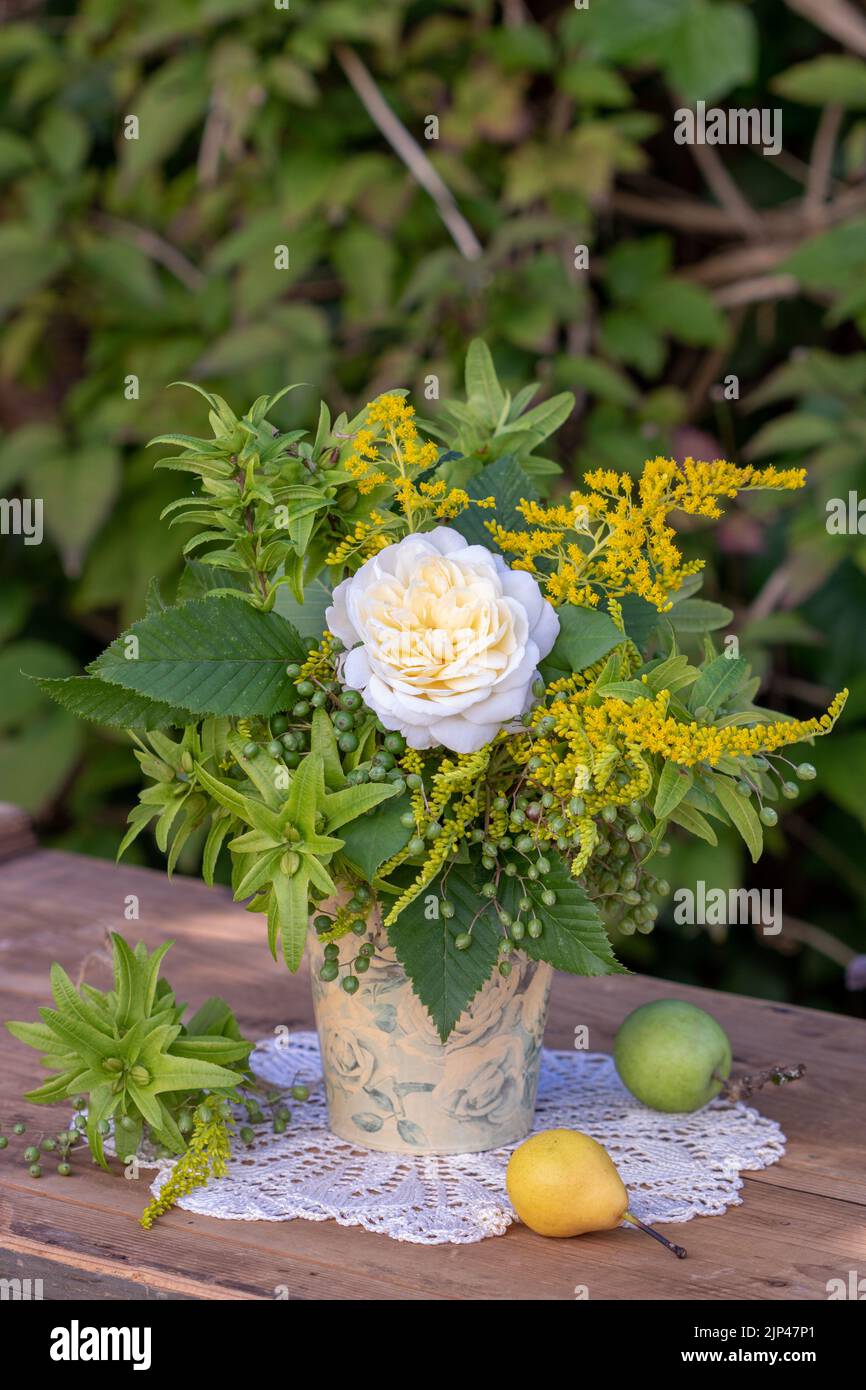 bouquet di rosa bianca, nocciola, bacca d'oro e bacche di sambuco in vaso in giardino Foto Stock