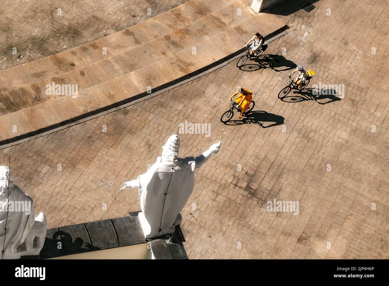 Una vista ad alto angolo di tre persone in bicicletta di fronte alle alte statue di Vienna, Austria Foto Stock