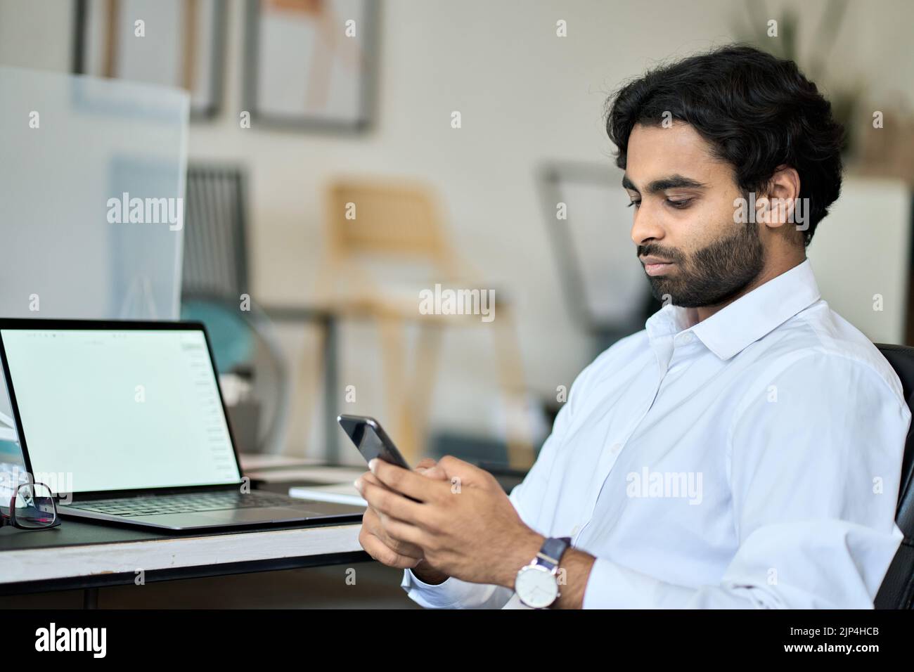 Dipendente business man indiano che utilizza la funzione di invio di messaggi tramite smartphone al lavoro. Foto Stock