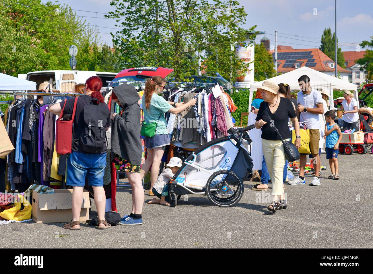 Heidelberg, Germania - Agosto 2022: Persone che guardano attraverso il rack con vecchi vestiti di seconda mano al mercato delle pulci Foto Stock