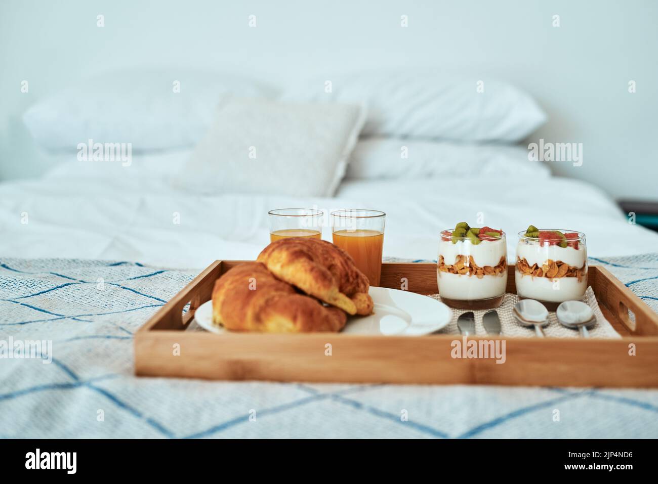 La colazione viene servita e una sana prima colazione su un vassoio di servizio su un letto. Foto Stock La colazione viene servita e una sana prima colazione su un vassoio di servizio su un letto. Foto Stock