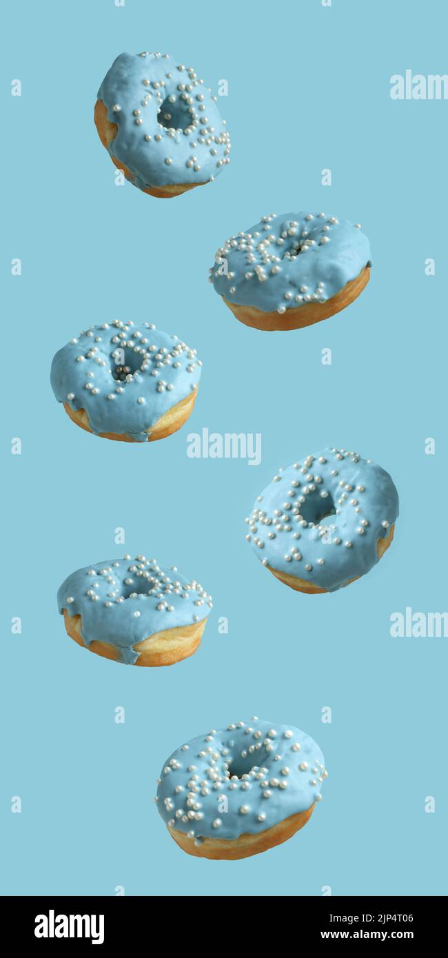 Ciambelle ricoperte di glassa blu pallido e cosparse di perle di zucchero su sfondo azzurro. Primo piano. Foto Stock