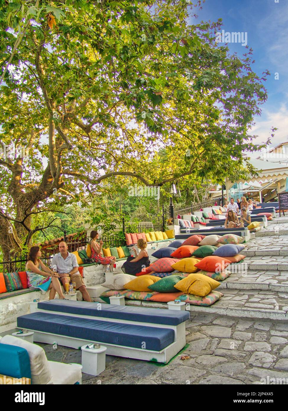 Una foto verticale di persone che riposano in un bar con cuscini nella città principale dell'isola di Skiathos, Grecia Foto Stock