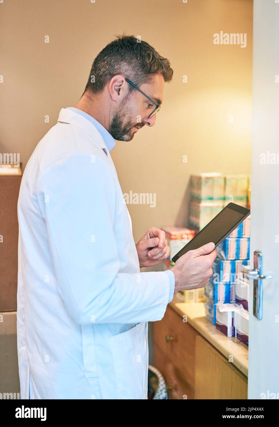 La ricerca farmaceutica è il modo in cui rimane all'avanguardia rispetto alla concorrenza: Un uomo maturo che utilizza un tablet digitale nel back Office di una farmacia. Foto Stock