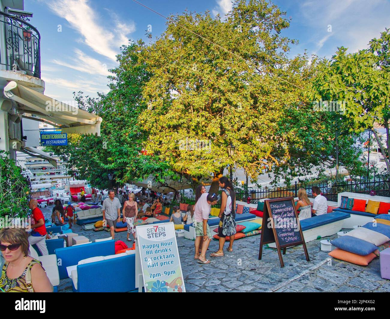 Molte persone riposano in un bar con cuscini colorati nella città principale dell'isola di Skiathos, in Grecia Foto Stock
