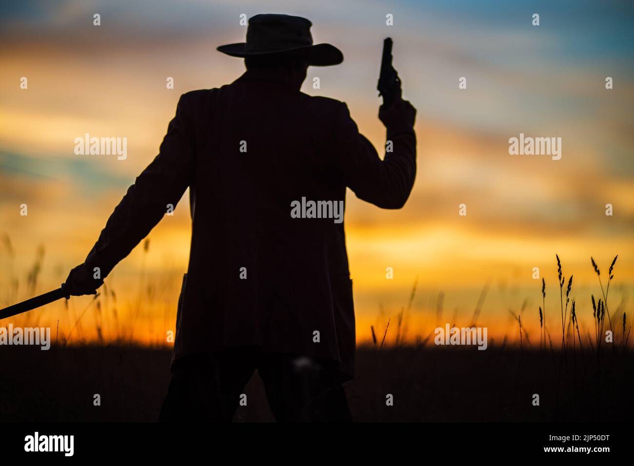 Silhouette di un demone e cacciatore di vampiri con un cielo spettacolare sullo sfondo. Un uomo con un katana e un revolver. Fantasia e concetto di Halloween Foto Stock